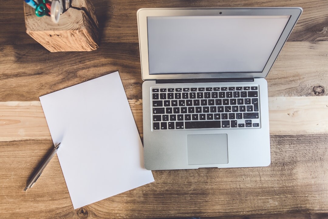 Flat lay of a notebook, pen and coffee cup on a wooden desk